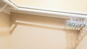 A corner of a room with a wooden floor, a white wall, and a white bench.