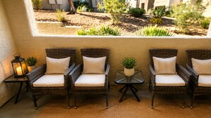 A seating area with wicker chairs and cushions, a small table with a plant, and a lantern on a side table.