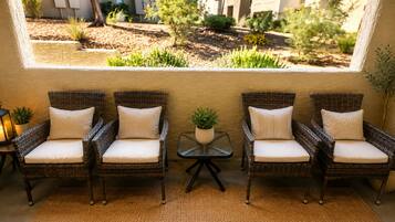 A seating area with wicker chairs and cushions, a small table with a plant, and a lantern on a side table.