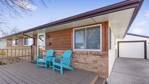 A wooden deck with two blue Adirondack chairs and a small table. - Knock's Hot Tub Haven in Loveland (Loveland)