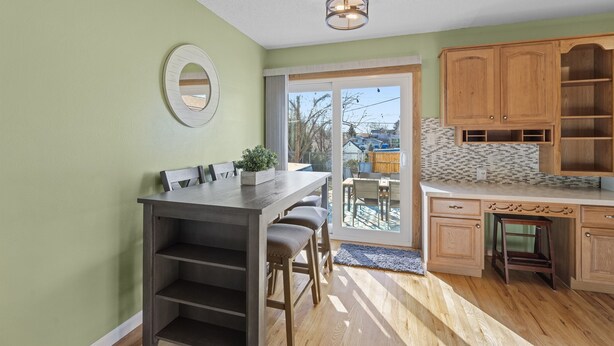 A kitchen with a dining table, chairs, wooden cabinets, and a view through the glass door. - Knock's Hot Tub Haven in Loveland (Loveland)