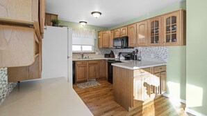 A kitchen with wooden cabinets, a refrigerator, a microwave, and a sink. - Knock's Hot Tub Haven in Loveland (Loveland)