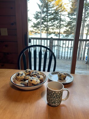 Enjoy meals in this dining area with a table set for a meal, featuring a plate of blueberry muffins and a mug.