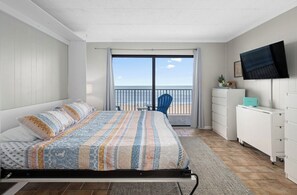 Ein Schlafzimmer mit Bett, Fernseher, Schreibtisch und einem Balkon mit Blick.