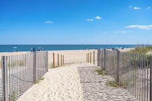 A sandy beach path leading to the sea, with a wooden fence on one side and beach umbrellas on the other. - Oceanfront Studio, King bed, Sleeps 4, Pool, Wi-Fi (Ocean City)