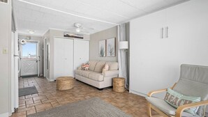 A spacious living area with a sofa, a rocking chair, and a door leading to a balcony. - Oceanfront Studio, King bed, Sleeps 4, Pool, Wi-Fi (Ocean City)