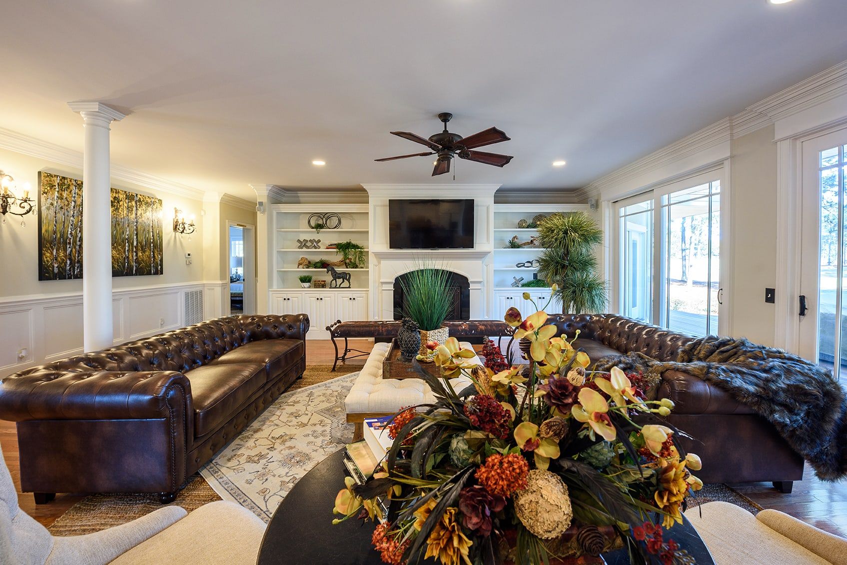 A spacious living room with a large sectional sofa, a fireplace, and a ceiling fan.