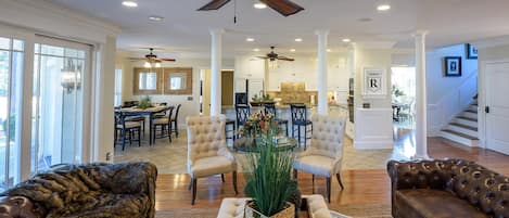 A spacious living room with a high ceiling fan, leather sofas, and a central coffee table.