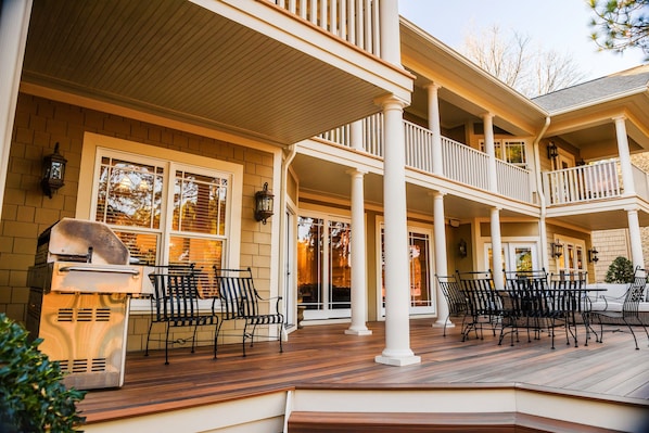 A covered outdoor area with multiple seating arrangements and a barbecue grill.