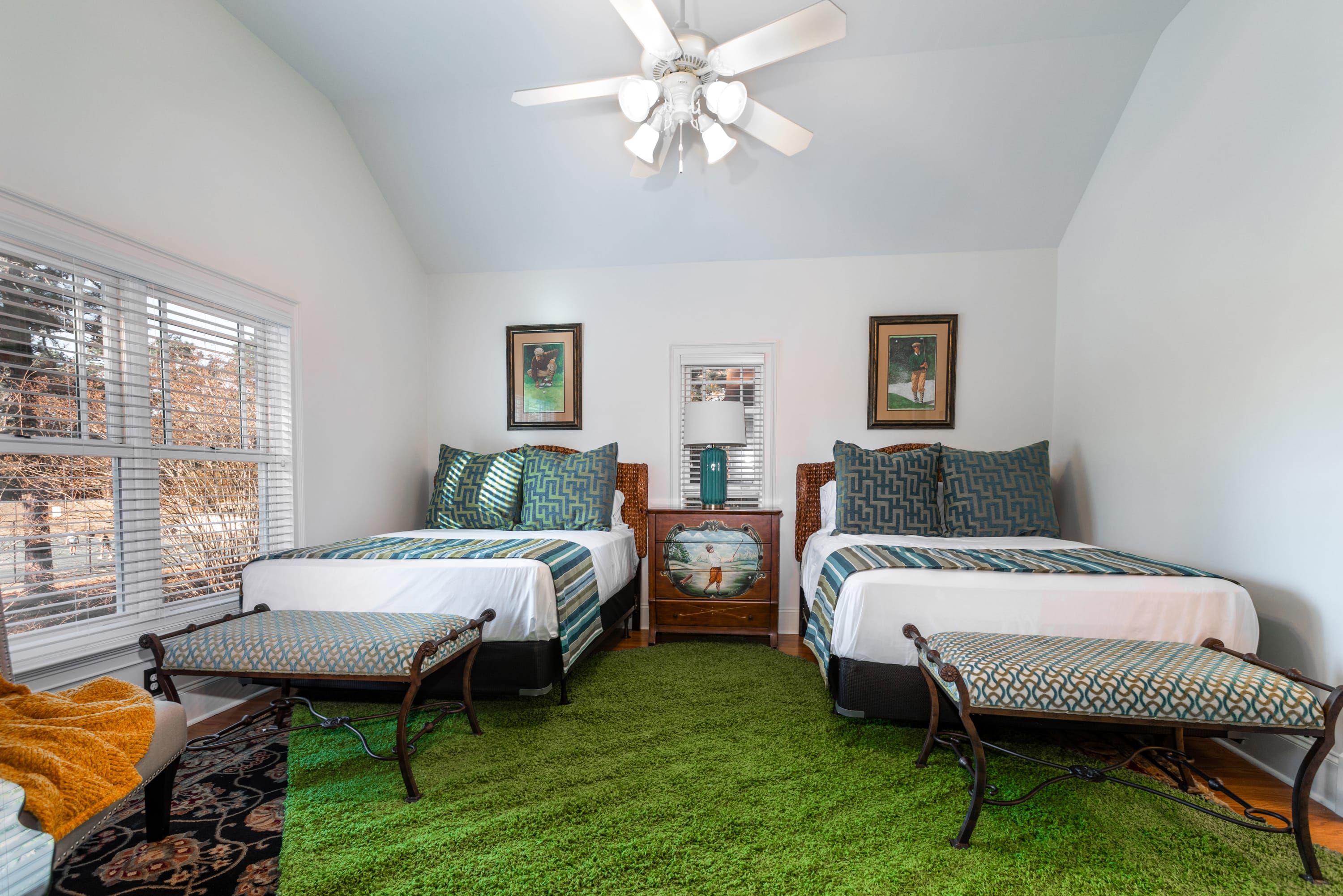 A bedroom with two beds, a ceiling fan, and a green artificial grass floor.