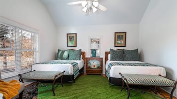 A bedroom with two beds, a ceiling fan, and a green artificial grass floor.