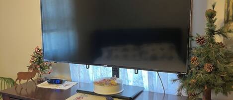 A television on a wooden cabinet with a floral curtain above it.