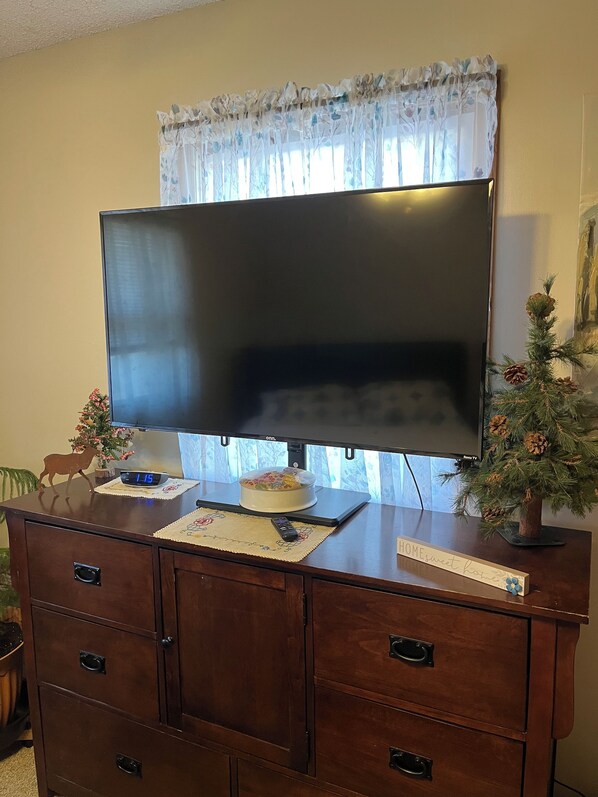 Un televisor sobre un mueble de madera con un cortinero floral.