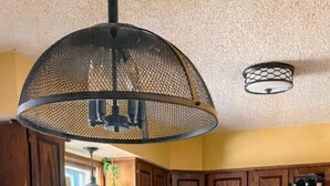 Ett kök med träskåp, ett vitt kylskåp, ett matbord med bordsunderlägg och en hängande lampa.