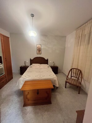 A bedroom with a bed, bedside tables, a wooden bench, a chair, a wall-mounted lamp, and a ceiling light fixture. - A house where you can enjoy Valdeorras, El Bierzo, or the Médulas Natural Park, (Pumares)