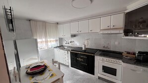 Une cuisine avec des meubles blancs, une cuisinière, un four et un évier.