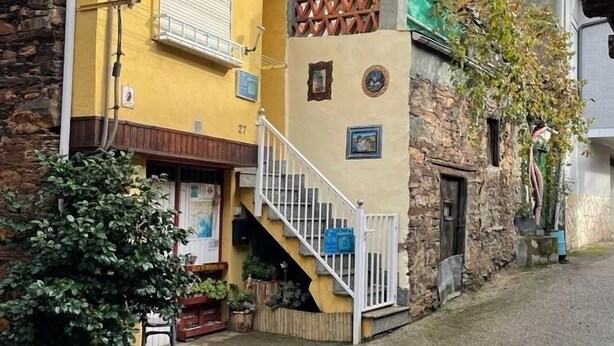 Un bâtiment à deux étages, doté d’une façade jaune, d’un mur en pierre et d’un petit escalier menant à l’étage supérieur.