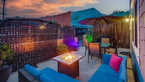 An outdoor patio area with blue seating, a fire pit, and a covered seating area with a table and chairs. - Mission Beach Steps to Beach Remodeled Home with AC, fireplace, and Parking (San Diego)
