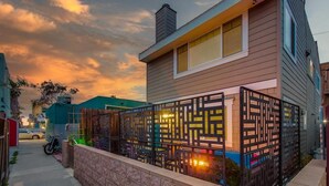 A modern house with a decorative black fence and a motorcycle parked outside. - Mission Beach Steps to Beach Remodeled Home with AC, fireplace, and Parking (San Diego)