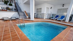Ein Hallenbad mit Fliesenboden, einer Treppe und Liegestühlen.