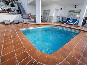 Una piscina interna con pavimento piastrellato, una serie di gradini e sedie a sdraio.