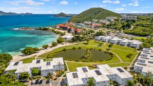 A coastal resort with multiple buildings, a marina, and a large body of water. - Crystal Cove At Sapphire Beach (St Thomas)