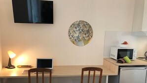 A compact kitchen with a microwave, a small refrigerator, and a flat-screen TV mounted on the wall. - Cozy and bright studio for 2 (Mulhouse)