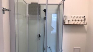 A glass-enclosed shower with a handheld showerhead and a wall-mounted towel rack. - Cozy and bright studio for 2 (Mulhouse)