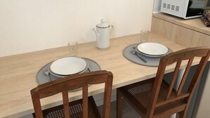 A dining table set with plates, a pitcher, and glasses, with chairs and a microwave in the background. - Cozy and bright studio for 2 (Mulhouse)