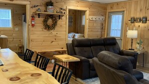 A cozy cabin interior with a wooden dining table, two leather sofas, and a small wooden table. - Modern Cabin located between Grindstone and Lac Courte Oreilles (Hayward)