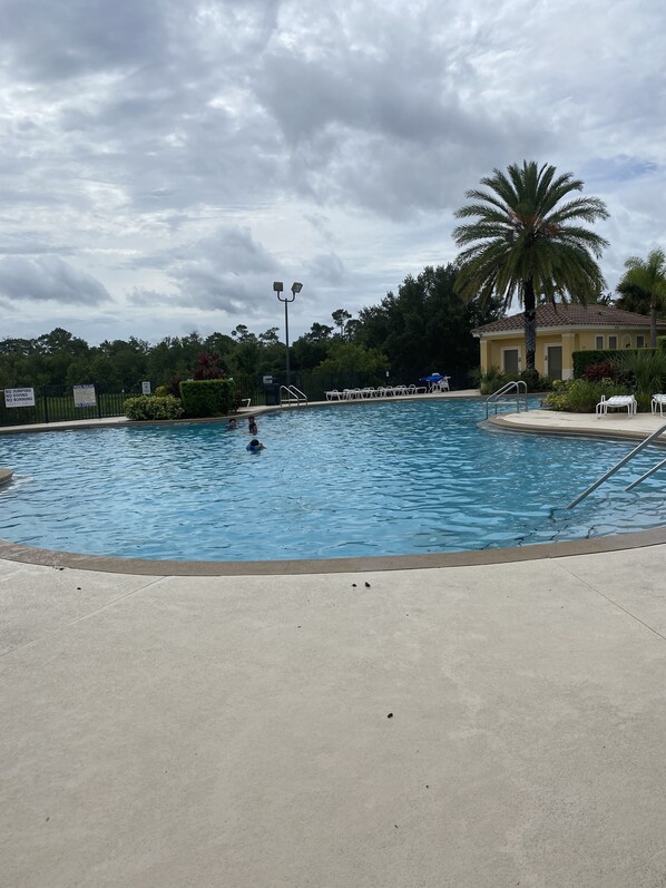 Una piscina con una palma e un edificio sullo sfondo.