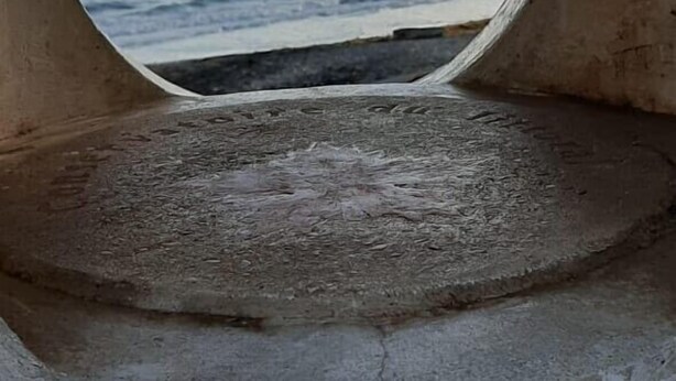 Une fenêtre circulaire offrant une vue sur la mer et une île lointaine.