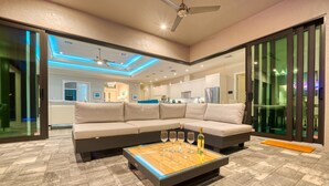 Un salon moderne avec un canapé d’angle, une table basse en verre et un ventilateur de plafond.