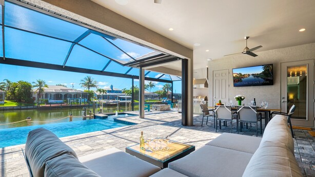 Un espace de détente extérieur moderne, doté d’une piscine, de coins salon et d’un espace repas.