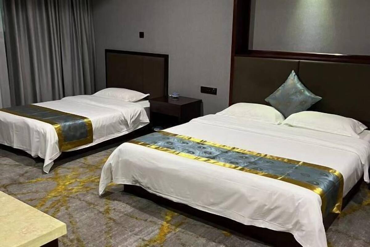A hotel room with two beds, a nightstand, and a carpeted floor.