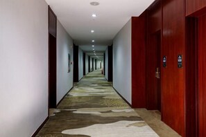 A long, narrow hallway with a patterned carpet and wooden doors on one side. - Jiutong Haiyuan International Hotel (Wuhan)