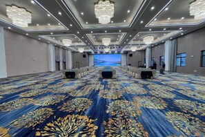 A large conference room with a patterned carpet, rows of tables, and a stage at the front. - Jiutong Haiyuan International Hotel (Wuhan)