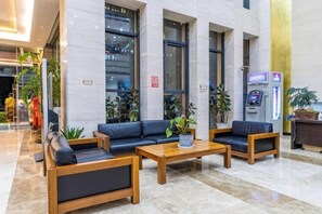 Eine Lobby mit einer Rezeption, einer Sitzecke und einem Self-Service-Terminal.