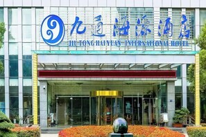 The exterior of the JiTong HaYuan International Hotel with a modern facade, large glass entrance, and a prominent logo. - Jiutong Haiyuan International Hotel (Wuhan)