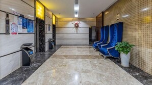 A hotel lobby with marble flooring, a reception desk, blue seating, and a potted plant. - Jiutong Haiyuan International Hotel (Wuhan)