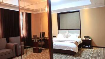 A hotel room with a large bed, a desk, a chair, and a mirror.