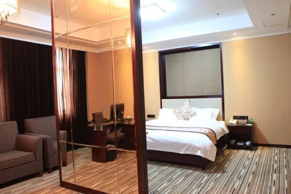 A hotel room with a large bed, a desk, a chair, and a mirror. - Jiutong Haiyuan International Hotel (Wuhan)