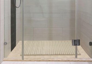 A glass-enclosed shower with a textured floor, a visible drain, and a metallic handle. - Jiutong Haiyuan International Hotel (Wuhan)