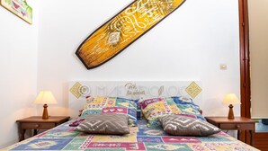 A bed with a colorful quilt and two pillows, flanked by nightstands with lamps. - Gîtes Papillon - Studio with swimming pool (Saint-François)