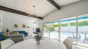 A modern living room with a large window, a round table, and a blue sofa. - Quintessential Midcentury Modern Alexander House (Palm Springs)