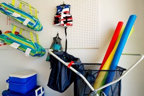 A storage area with various bags and mats, a metal rack, and a blue cooler. - 🌟 STUNNING!- Game Room, Pool, Beaches & Full Remodel! (Bradenton)