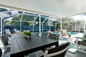 A covered patio area with a pool, outdoor furniture, and a table. - 🌟 STUNNING!- Game Room, Pool, Beaches & Full Remodel! (Bradenton)