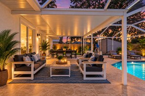 An outdoor patio with a pool, furnished seating, and ambient lighting. - STUNNING! Game Room, Pool, Beaches & Full Remodel! (Bradenton)