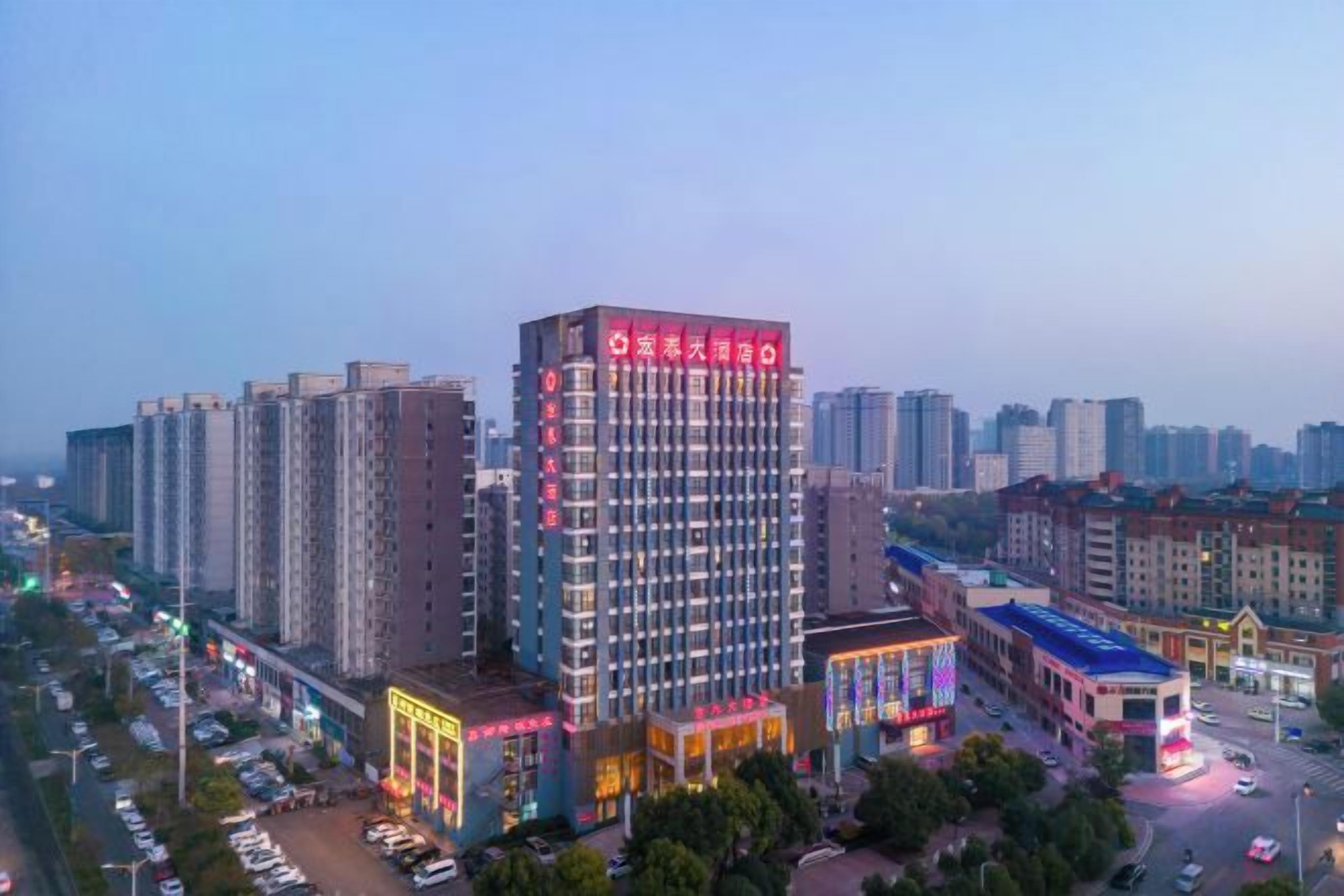 A high-rise hotel with multiple floors, a prominent entrance, and a surrounding urban environment with other buildings and a street.