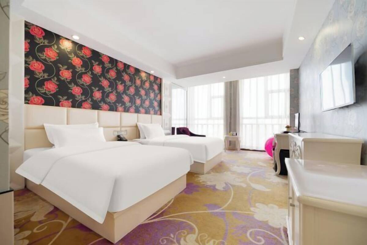 A hotel room with two beds, a large floral-patterned wall, and a modern design.
